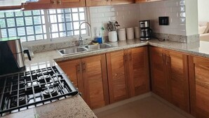 A modern kitchen with wooden cabinets, a stainless steel stove, and a granite countertop.