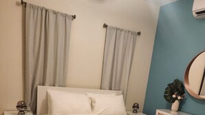 A bedroom with a bed, nightstands, a dresser, a mirror, and curtains.