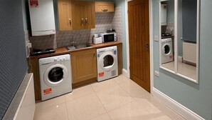 A compact kitchen with wooden cabinets, a microwave, a washing machine, and a small sink.