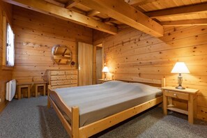 Ein Schlafzimmer einer Holzhütte mit einem Bett, einem Schminktisch und zwei Nachttischlampen.