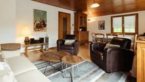 A cozy living room with leather sofas, a coffee table, and a dining area with wooden furniture.