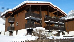 A modern multi-story building with balconies, surrounded by snow.