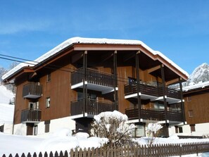 Ein modernes, mehrstöckiges Gebäude mit Balkonen, umgeben von Schnee.