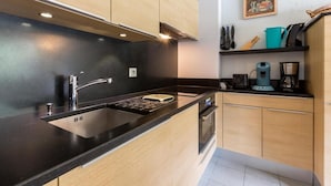 A modern kitchen with black countertops, wooden cabinets, a stainless steel sink, and a built-in oven.