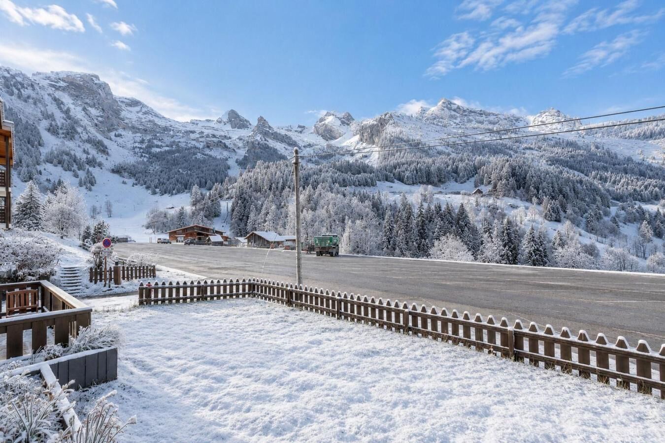 A snow-covered landscape with a road, buildings, and mountains.
