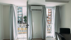 A room with a sliding glass door leading to a balcony, an air conditioning unit mounted above the door, and a black chair in the corner. - Maison Work & Travel 1 - Palermo (Buenos Aires)