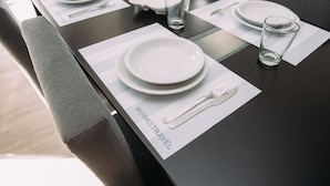 A neatly set dining table with plates, cutlery, and glasses, and a placemat with the words "WORK&TRAVEL". - Maison Work & Travel 1 - Palermo (Buenos Aires)