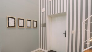 A hallway with striped walls, a white door, and four framed artworks on the wall. - Maison Work & Travel 1 - Palermo (Buenos Aires)