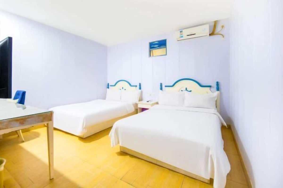 Une chambre d’hôtel avec deux lits simples, un bureau, une chaise et un téléviseur.