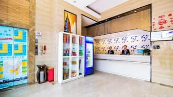 A hotel reception area with a reception desk, a map, vending machines, and a wall with decorative elements.