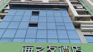 A hotel facade with a green signboard displaying Chinese characters.
