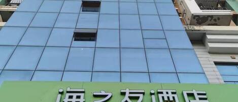 A hotel facade with a green signboard displaying Chinese characters.