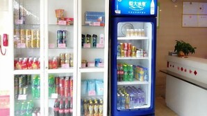 A vending machine stocked with various beverages and a refrigerated display case in a hotel lobby.