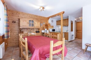 A cozy room with a bed, wooden furniture, a kitchenette, and a wooden wall.
