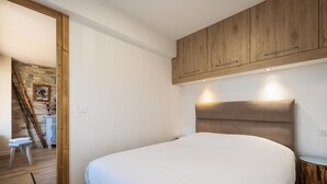 A bedroom with a large bed, wooden headboard, and a small bedside table. - 1st floor, view mountain, balcony, tv, ski locker, 37m², La Clusaz (La Clusaz)