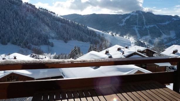 A wooden deck overlooking a snowy mountain landscape with cabins. - 1st floor, view mountain, balcony, tv, ski locker, 37m², La Clusaz (La Clusaz)