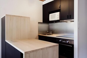 A compact kitchen with a wooden countertop, a sink, a microwave, and a stove.