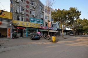 Vista de la calle con un edificio que cuenta con varias tiendas, incluyendo el Hotel Internacional UCC.