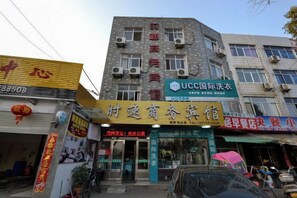 Un edificio de varios pisos con diversos comercios en la planta baja, incluyendo una tienda UCC International Dry Goods y un restaurante.