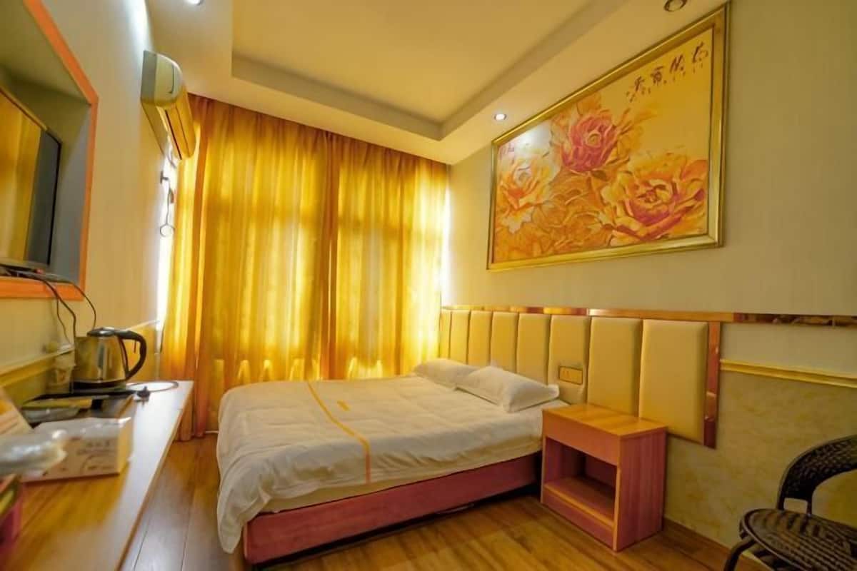 Ein Hotelzimmer mit Bett, Nachttisch, Sessel und einem Bild an der Wand.