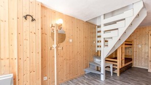 A wooden interior with a staircase, a floor lamp, and a radiator.