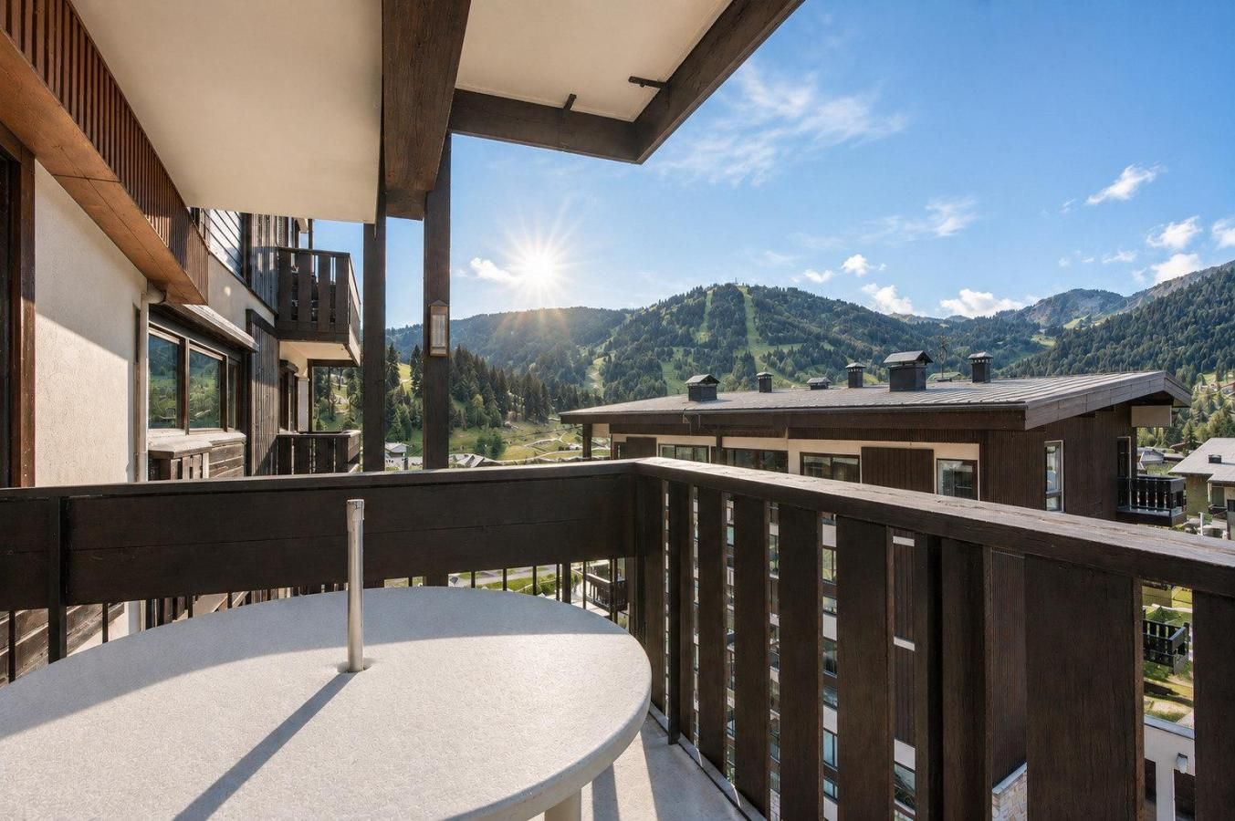 Een balkon met een tafel en stoelen, met uitzicht op een bergachtig landschap en een heldere lucht.