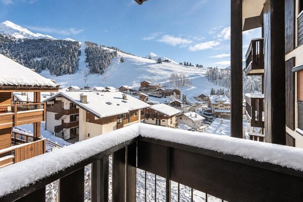 A snow-covered mountain village with wooden buildings and a clear view of the surrounding landscape.