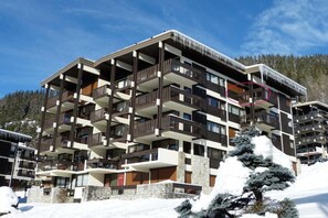 A multi-story hotel with balconies, stone facade, and snow-covered surroundings.