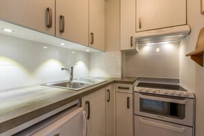A modern kitchen with a built-in oven, a sink, and white cabinetry.