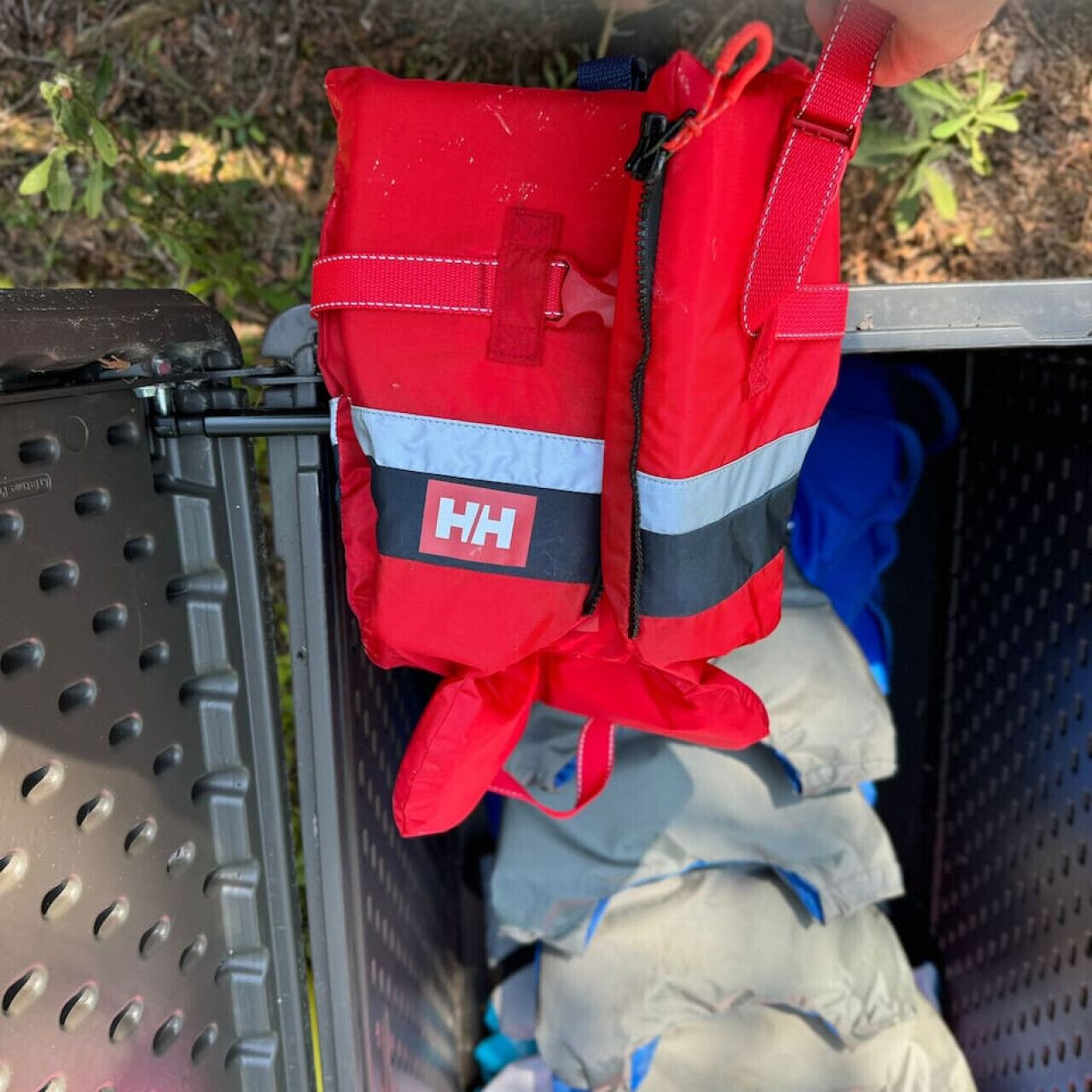 A red bag with a reflective strip and the letters "HH" on it, hanging from a metal structure.