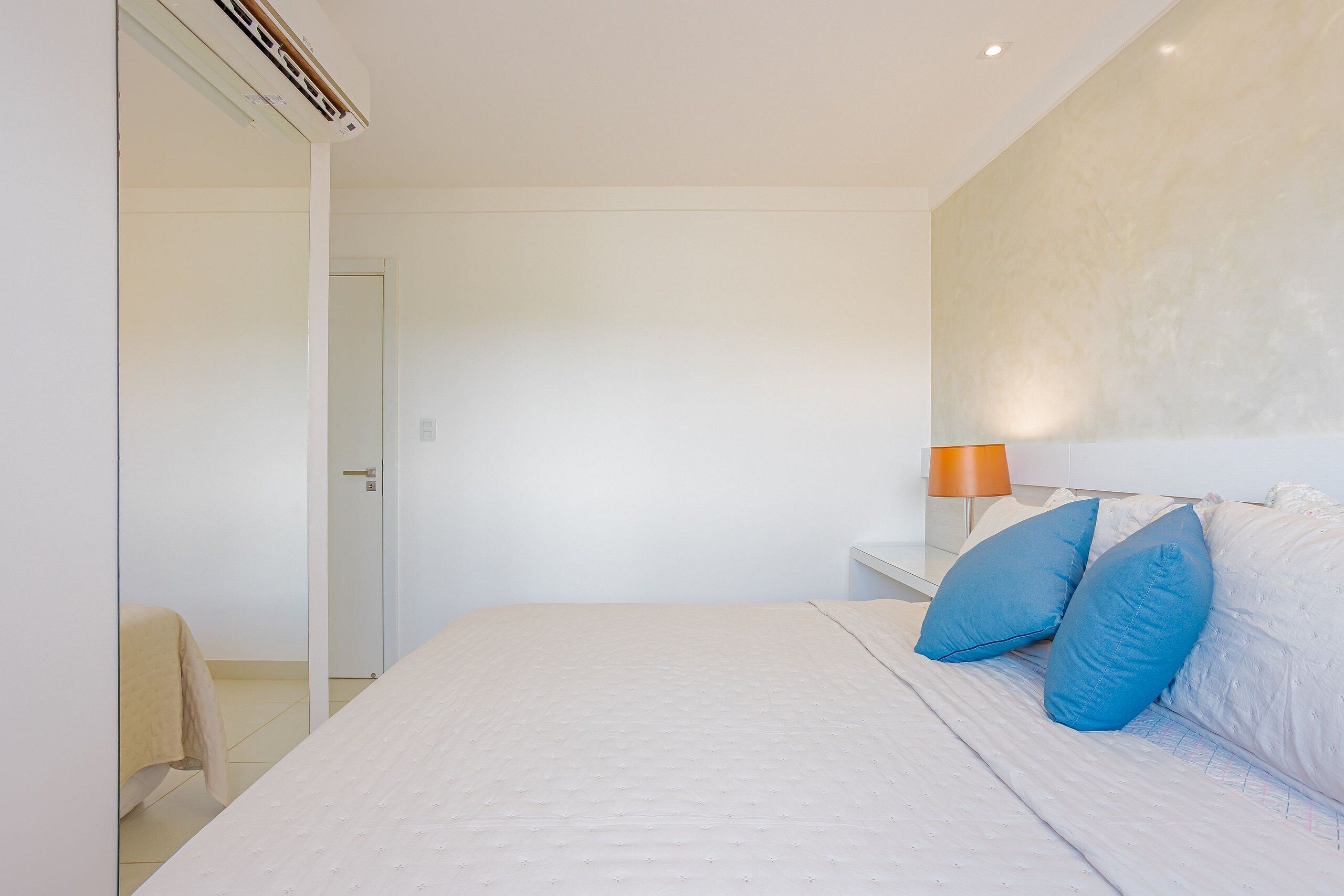 Ein Schlafzimmer mit einem großen Bett, einem Nachttisch mit Lampe und einer Tür zu einem anderen Raum.