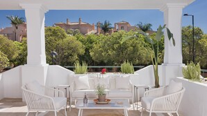 An outdoor seating area with white wicker furniture, a woven rug, and a potted plant. - 3 Bedroom, 3 Bathroom Beachside Apartment (Estepona)