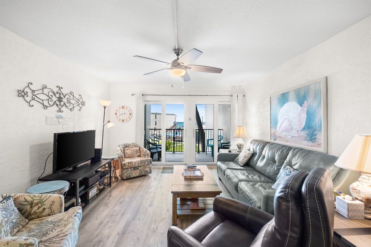 A living room with a television, leather sofa, and a painting.