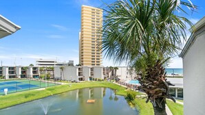 A courtyard with a tennis court, a small pond, and a palm tree. - 3BR Sleeps 8 | Sugar Beach | Steps to Beach & Pool (Panama City Beach)