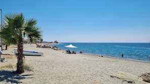 En sandstrand med en palme, et hvidt telt og en båd.