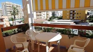 Un balcón con mesa y sillas, con vista a una zona residencial con edificios y zonas verdes.