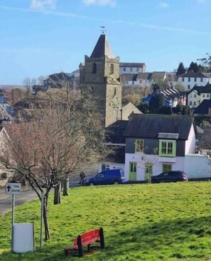 Un'area erbosa con una panchina, un cartello stradale e un edificio con una torre.