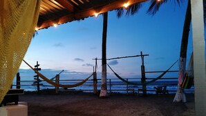 A beach view with a hammock, wooden fence, and a signpost.