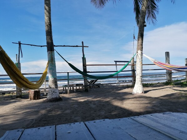Una playa con hamacas y una terraza de madera.