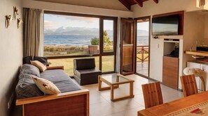 A room with a sofa, a small table, and a view of the sea.