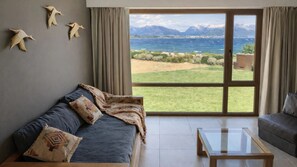 Una sala de estar con un sofá, una mesa de centro y vistas a un paisaje montañoso a través de un ventanal.