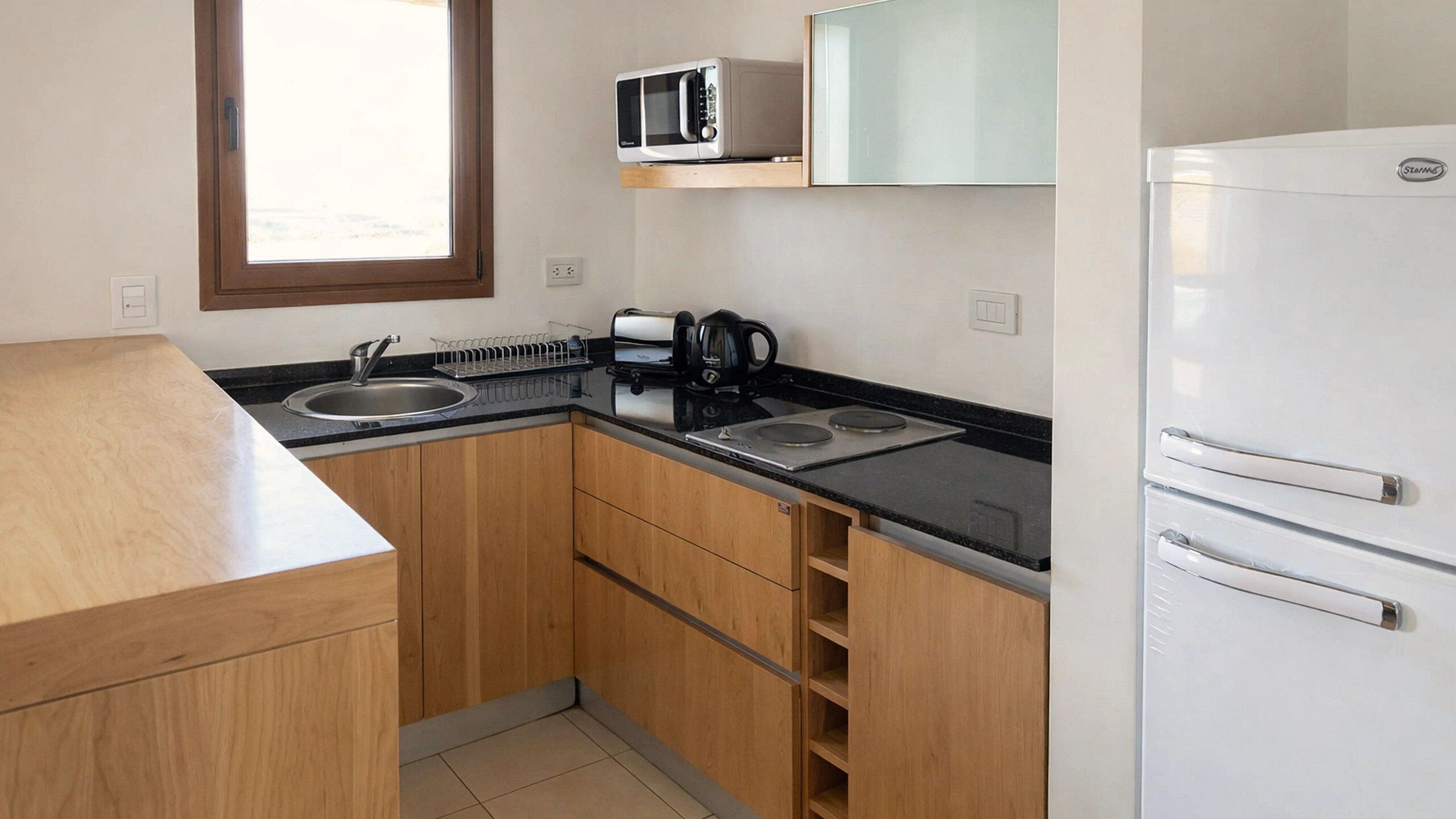 A compact kitchen with a sink, a microwave, a coffee maker, and a refrigerator.
