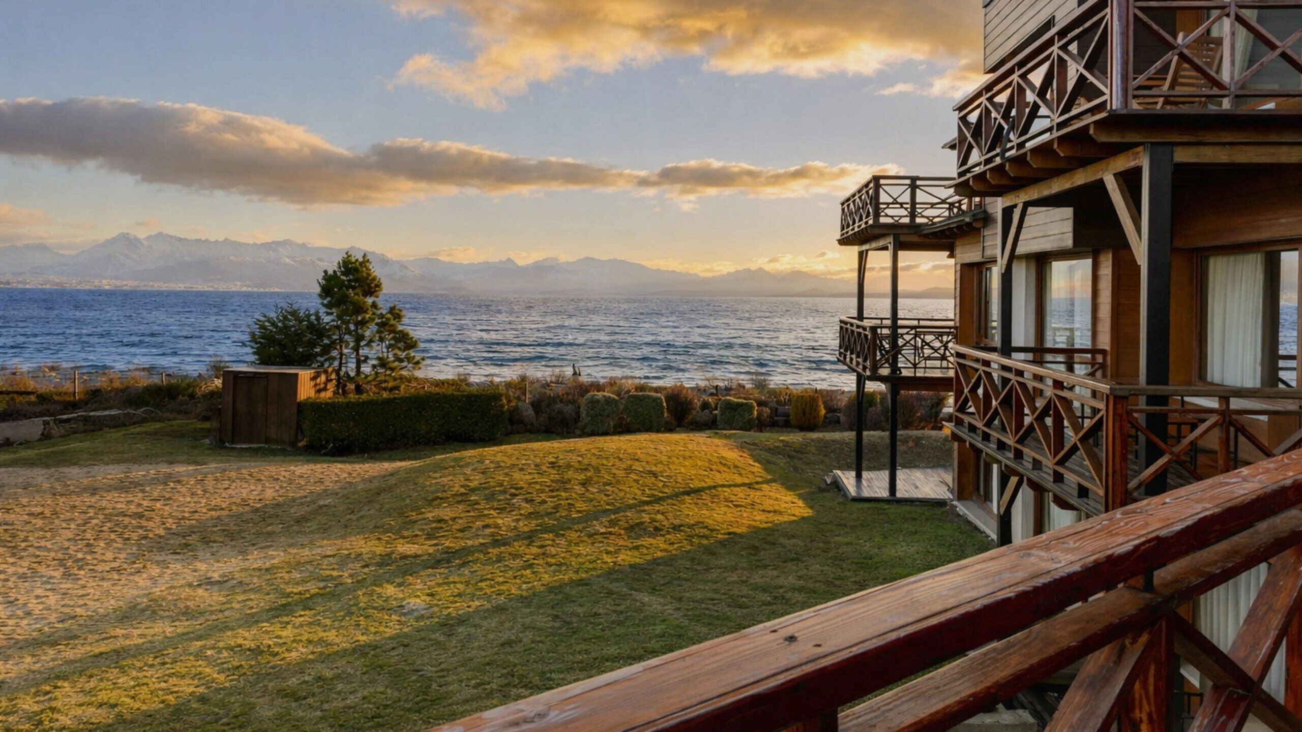 Una terraza de madera con vistas al mar y a las montañas.