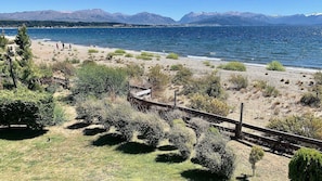 Een kustlandschap met een strand, bergen op de achtergrond en een houten hek.