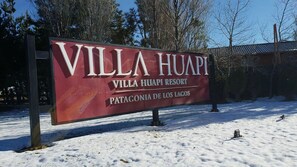 Een bordje van Villa Huapi Resort met een helder zicht op het besneeuwde landschap.