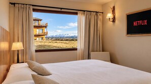 A hotel room with a bed, a view of mountains, a balcony, and a wall-mounted Netflix sign. - Garden Superior Moreno Ground Floor Lake Front (Dina Huapi)