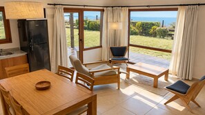 A dining area with a wooden table and chairs, a refrigerator, and a view of the outdoors. - Garden Superior Moreno Ground Floor Lake Front (Dina Huapi)