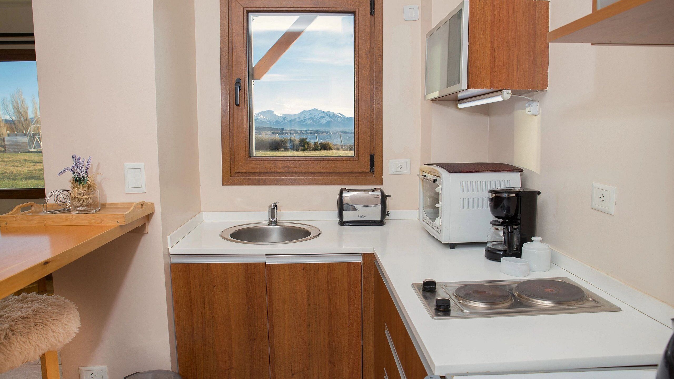 Una kitchenette compacta con un lavamanos, una tostadora, una cafetera y una estufa.