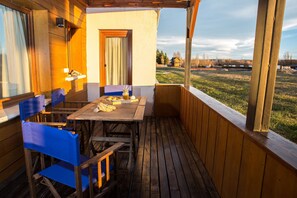 Enjoy dining and socializing on this deck with a table and chairs, surrounded by a lush greenery and a scenic view.