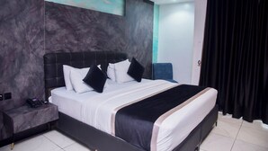 A modern hotel room with a large bed, a nightstand, and a blue chair.